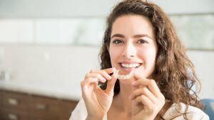 Woman holding clear Invisalign aligner smiling with perfect teeth, demonstrating what is Invisalign treatment.