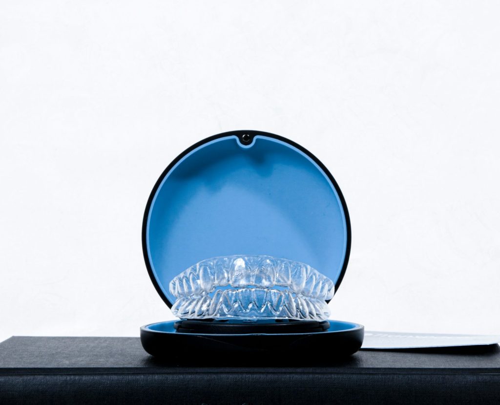 What is Invisalign – clear aligners stored in a protective blue case on a black surface